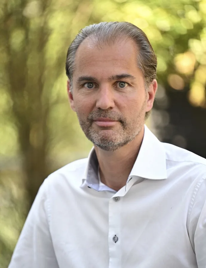 Michael Gruninger im weißen Hemd, Porträt im Freien vor grünen Bäumen